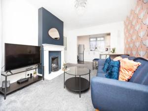 a living room with a blue couch and a tv at Pass the Keys Beautifully refurbished house close to Airport in Manchester