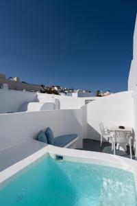 ein Pool auf dem Dach eines Hauses mit einem Tisch in der Unterkunft White Concept Caves in Fira