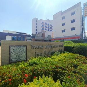a sign in front of a building with some flowers at Mayflower Grande Hotel Phitsanulok in Phitsanulok