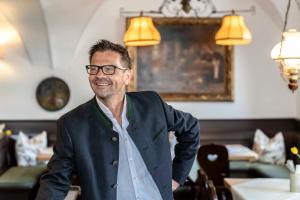 a man wearing glasses standing in a room at Hotel Alter Wirt in Weyarn