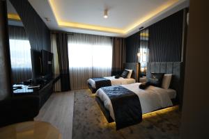 een hotelkamer met 2 bedden en een televisie bij Marlen Hotel Bayraklı in Bayrakli