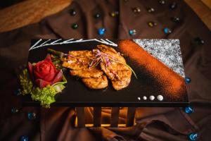 a black plate of food with chicken and a rose at De Mandarin Beach Resort Suites & Villas, Candolim in Candolim