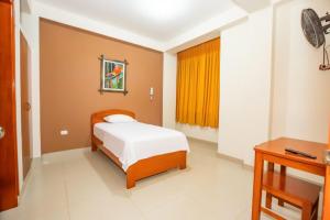 Dormitorio pequeño con cama y mesa en Shilcayo Comfort Hospedaje, en Tarapoto