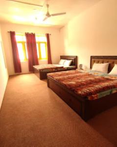 a hotel room with two beds and two windows at Hotel City Way, Srinagar in Srinagar
