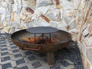 uma mesa enferrujada sentada em frente a uma parede de pedra em Chatka - A - Vyhlídka nad řekou em Zdiby