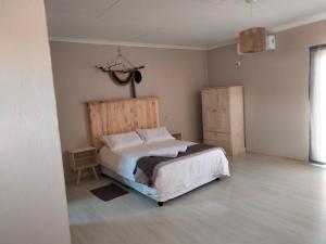 um quarto com uma cama branca e uma cabeceira em madeira em Rustic Stone Lodge em Thabazimbi