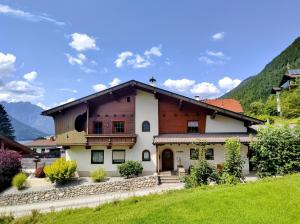 a large white house with mountains in the background at Ferienwohnung Bergzauber in Maurach