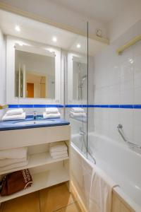 a bathroom with a sink and a tub and a mirror at Résidence Pierre & Vacances Les Rivages Du Parc in Menton