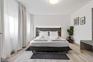 BRIGHT Herzogenaurach Zentrum في هيرتسوجيناوراخ: غرفة نوم بسرير بجدران بيضاء وستائر بيضاء