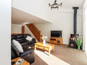 sala de estar con sofá de cuero negro y chimenea en The Milking Parlour, en Cranbrook