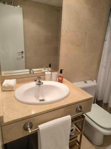 Un baño con lavabo, inodoro y espejo. en Balay Apartment Benidorm, en Benidorm