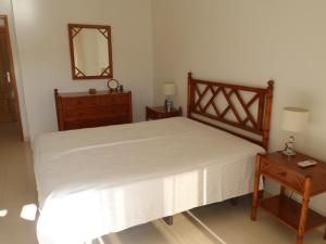 Schlafzimmer mit einem Bett, einer Kommode und einem Spiegel in der Unterkunft Apartamento Varandas do Sol Nascente in Porches
