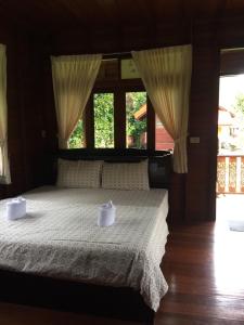 a bedroom with a bed with white sheets and windows at Phet Ban Suan Hotel in Ko Chang