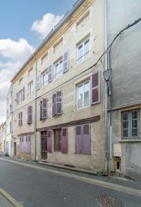 stary budynek z fioletowymi drzwiami i oknami wychodzącymi na ulicę w obiekcie Le Bon Enfant - Appartements design en centre ville w mieście Cusset
