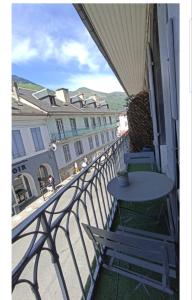 een balkon met een tafel en stoelen en gebouwen bij L'Étape du Tourmalet in Luz-Saint-Sauveur