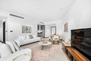 een woonkamer met witte meubels en een televisie bij Meerak Homes - Glamorous 2 bed Apartment with Panoramic Views - Business Bay with free Wifi, Parking, Gym and Pool in Dubai