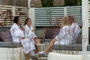 Tres mujeres con batas blancas sentadas en un patio en Säröhus Hotel, Conference & Spa en Särö