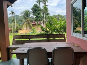 a wooden table and chairs on a porch with a window at Phet Ban Suan Hotel in Ko Chang