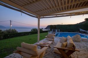 a patio with a table and chairs and a pool at Ionian Calm Villas in Vasiliki