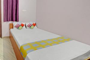 Super OYO Hotel Happy Inn في باتنا: غرفة نوم مع سرير أبيض كبير مع وسائد ملونة