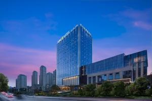 a tall glass building in front of a city at Home2 Suites by Hilton Guiyang Guanshanhu in Guiyang