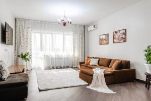 a living room with a brown couch and a wedding dress at Aray apartment in Almaty