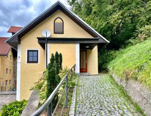 ein kleines gelbes Haus mit einer roten Tür auf einem Hügel in der Unterkunft Ferienhaus am Fluss in Pinsdorf