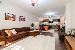 a living room with a brown couch and a kitchen at Aray apartment in Almaty