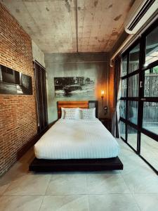 a large bed in a room with a brick wall at Yotaka The Hostel in Bangkok