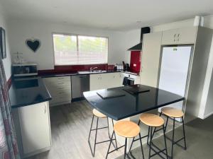 uma cozinha com uma mesa preta e bancos em 4bed 2bath house 5 mins walk to Palms & Golf club em Christchurch