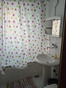 baño con lavabo y cortina de ducha con flores en Karic apartman, en Paraćin