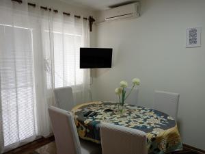 una mesa de comedor con un jarrón de flores. en Karic apartman, en Paraćin