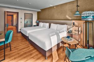 um quarto com uma cama grande, uma mesa e cadeiras em Doubletree By Hilton Antalya City Centre em Antalya