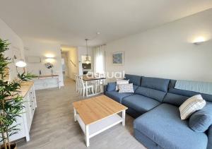 ein Wohnzimmer mit einem blauen Sofa und einem Tisch in der Unterkunft LAS PALOMAS 1-2 in Platja  d'Aro