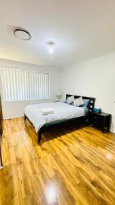 Quiet family Townhouse in Wollongong CBD في ولونغونغ: غرفة نوم بسرير وارضية خشبية