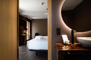 a bedroom with a bed and a sink and a mirror at Hotel Atari in Donostia-San Sebastián