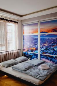 een slaapkamer met een groot raam met uitzicht op de stad bij Apartment Ada - at the heart of downtown Sarajevo in Sarajevo