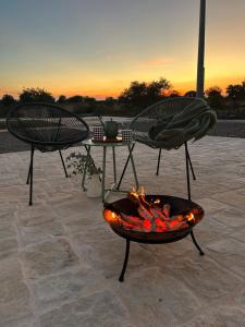 a fire pit with two chairs and a table at Trulli Enjoy in Noci