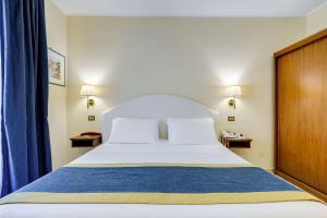 a bedroom with a large bed and blue curtains at Best Western Hotel La Solara in Sorrento