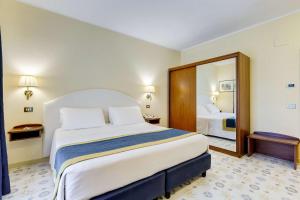 a hotel room with a large bed and a mirror at Best Western Hotel La Solara in Sorrento