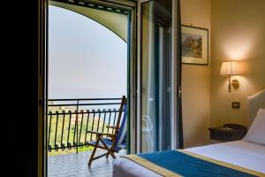 a bedroom with a balcony with a bed and a chair at Best Western Hotel La Solara in Sorrento