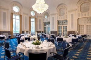 a banquet hall with white tables and chairs and a chandelier at Dorint Resort & Spa Bad Brückenau in Staatsbad Brückenau