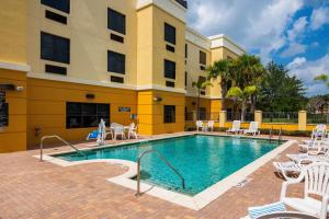 une piscine dans un hôtel avec des chaises et un bâtiment dans l'établissement Comfort Suites Vero Beach I-95, à Vero Beach