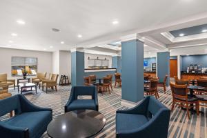 a lobby with blue chairs and tables and a restaurant at Comfort Suites Vero Beach I-95 in Vero Beach