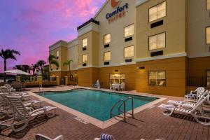 a pool in front of a hotel with chairs at Comfort Suites Vero Beach I-95 in Vero Beach