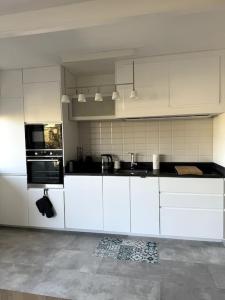 uma cozinha com armários brancos e electrodomésticos pretos em Appartement neuf avec balcon et parking privé em Caen