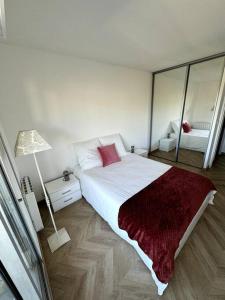 um quarto branco com uma cama grande e um espelho em Appartement neuf avec balcon et parking privé em Caen