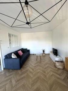 uma sala de estar com um sofá azul e uma televisão em Appartement neuf avec balcon et parking privé em Caen