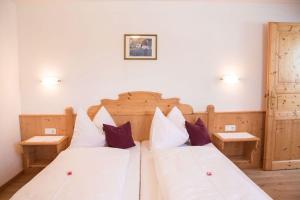 フラッハウにあるHaus Bliemのベッドルーム1室(白いシーツと紫色の枕が備わるベッド2台付)