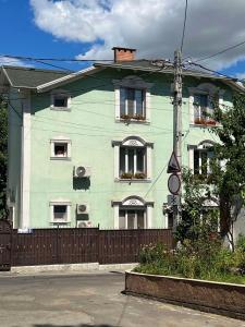 ein grünes Haus mit Fenstern und einem Zaun in der Unterkunft Комната Gold Rose in Chişinău